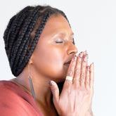Woman with braided hair and pink nail polish holding her hands together inhaling an aromatherapy scent.