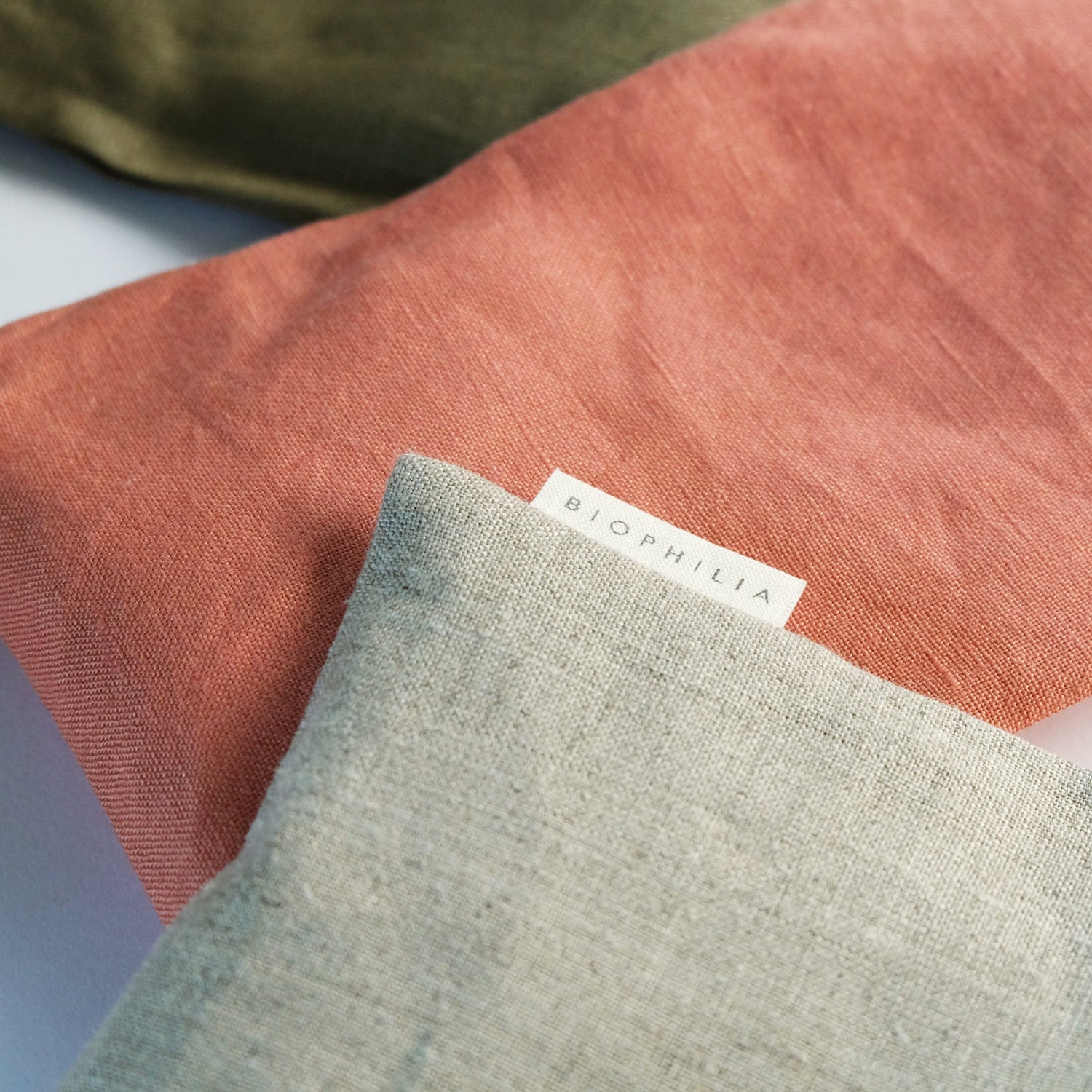Close up of three linen covered eye pillows with a &