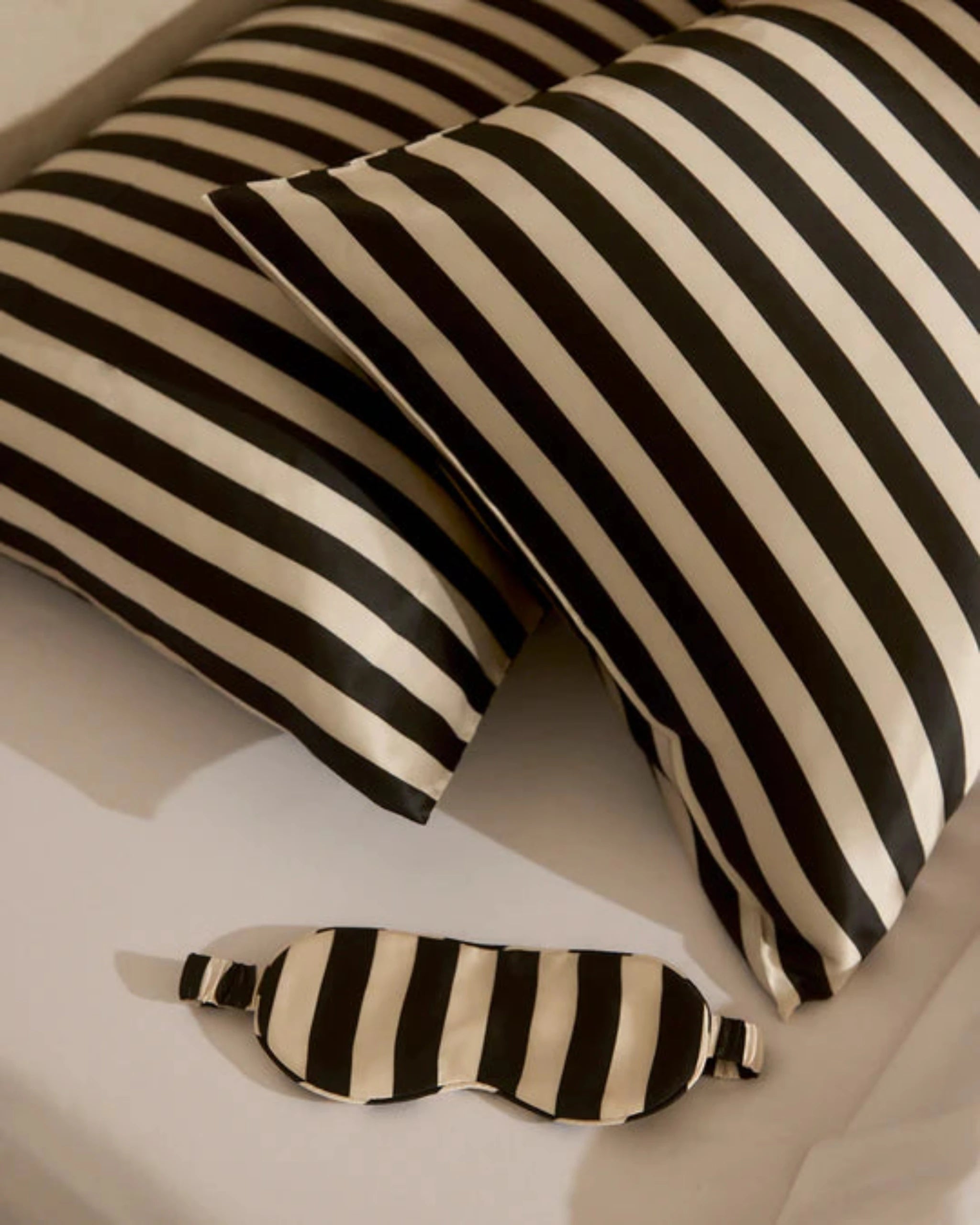 Black and white striped eye mask and pillow on a light background