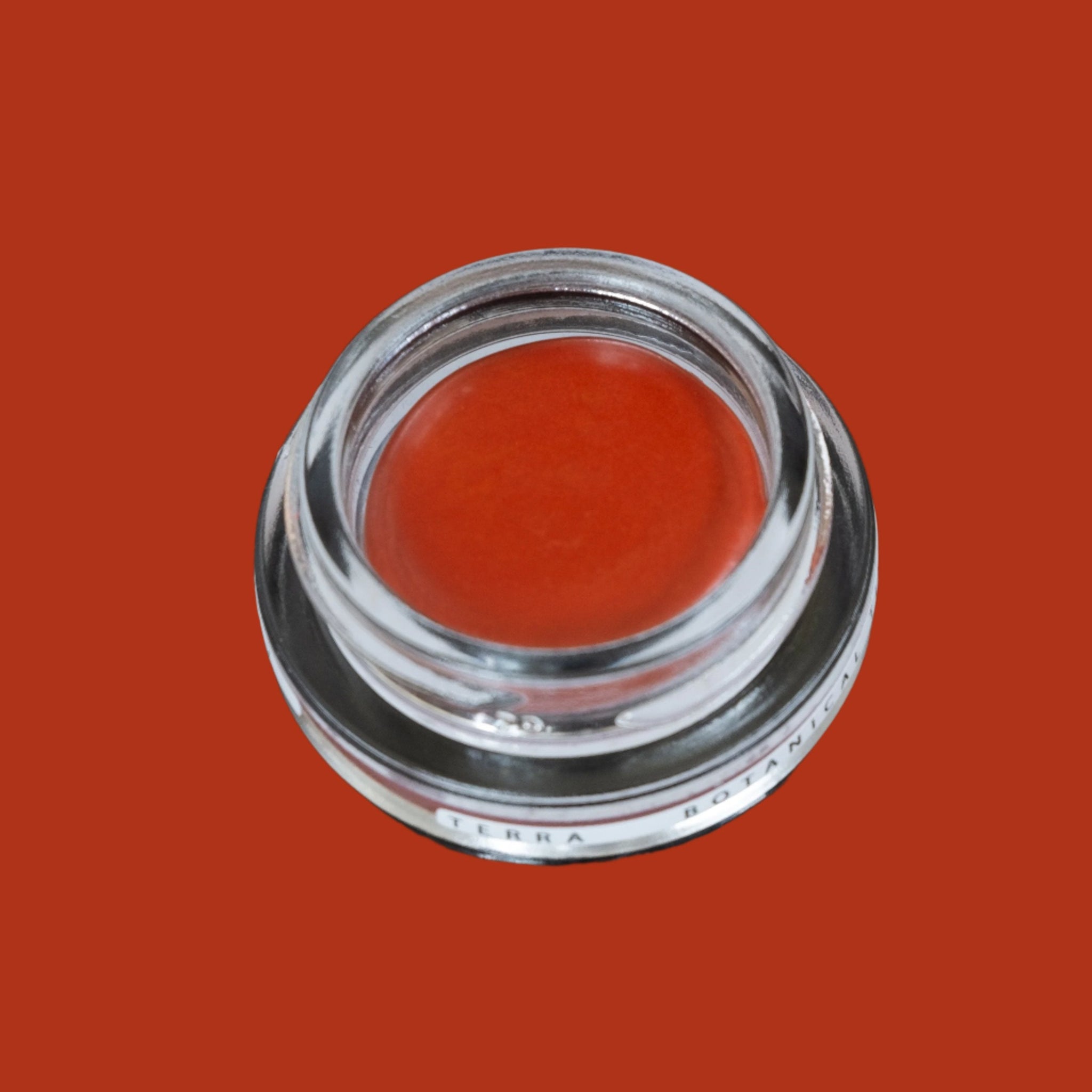 Glass pottle of Terra lip tint, an earth, orange, red colour.