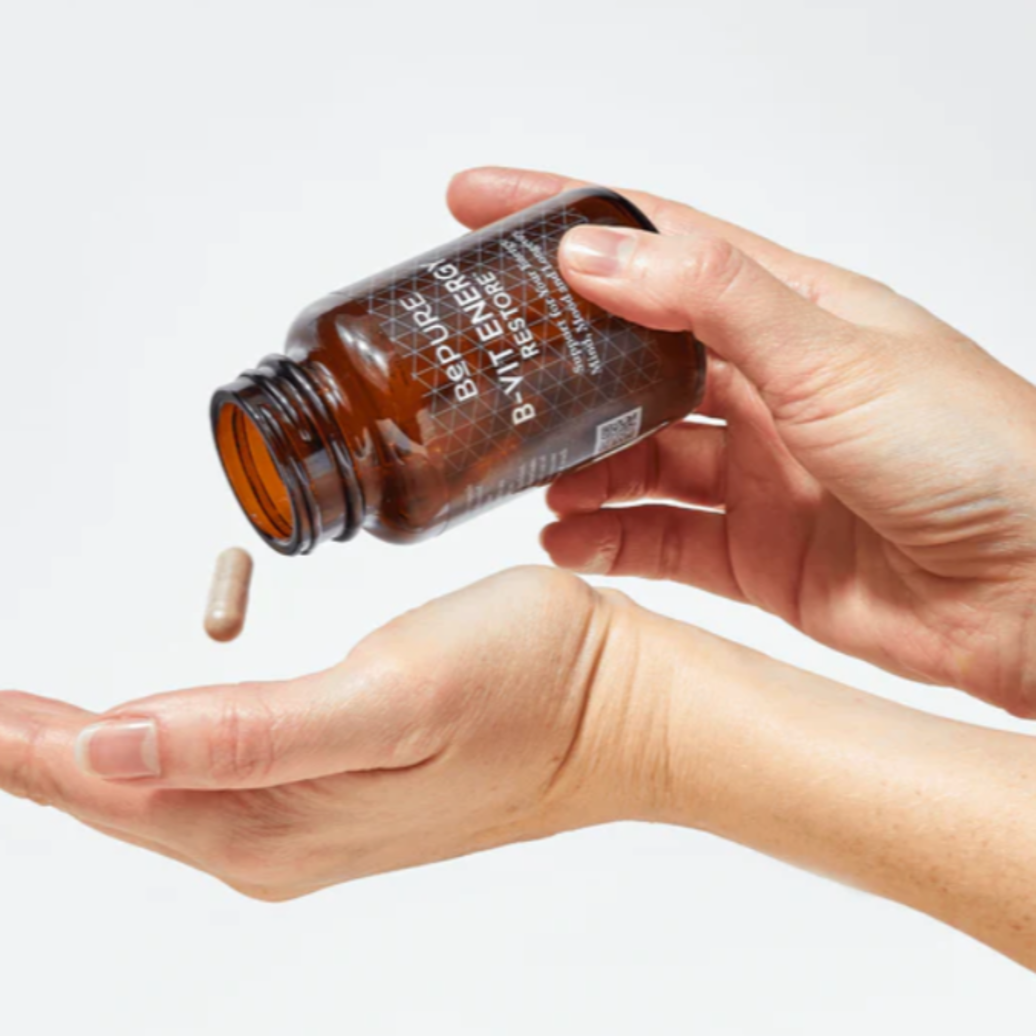 Hand holding an amber glass bottle labeled &