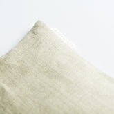 Close-up of beige linen eye pillow with BIOPHILIA label on a white background