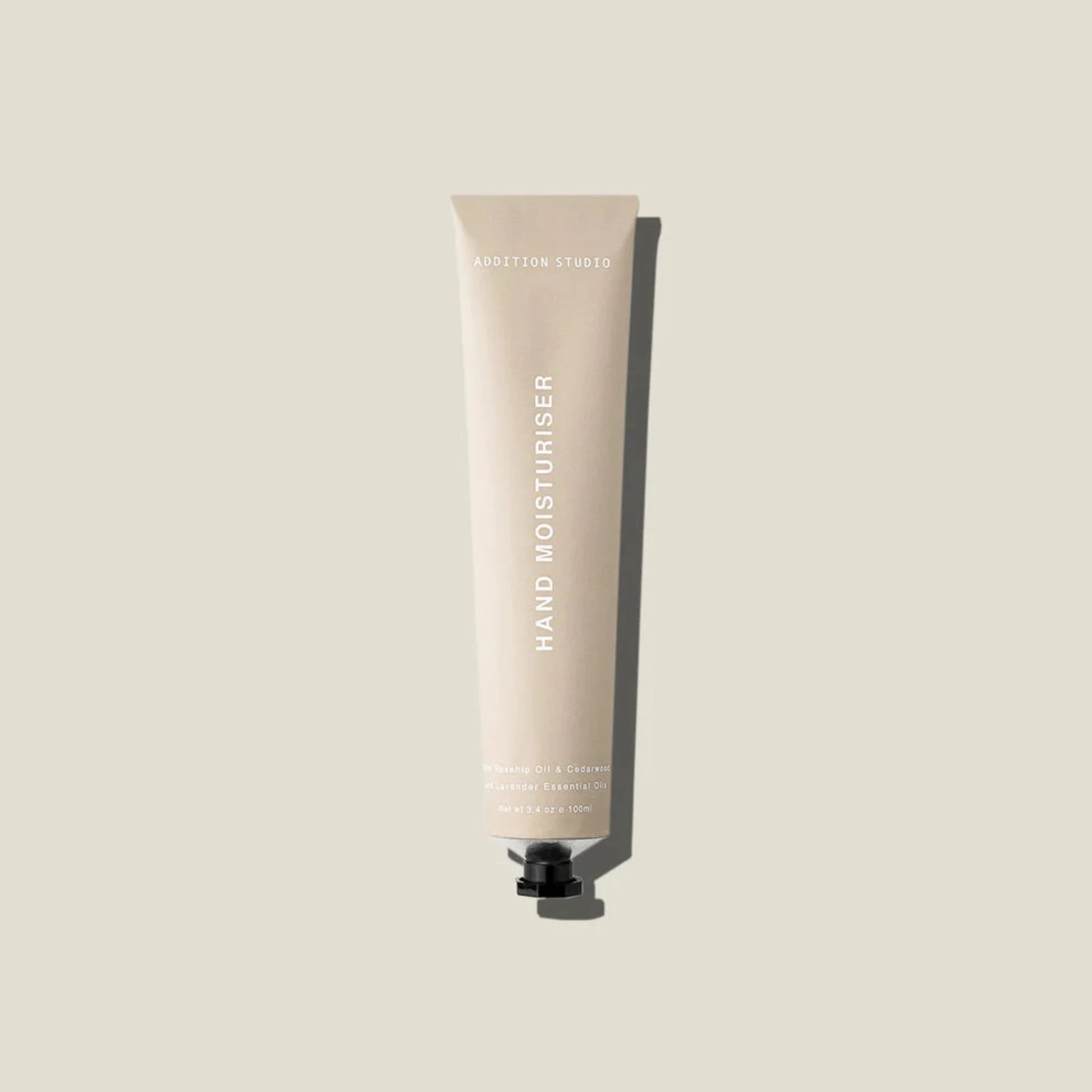An oat coloured tube of hand moisturiser on a beige surface.