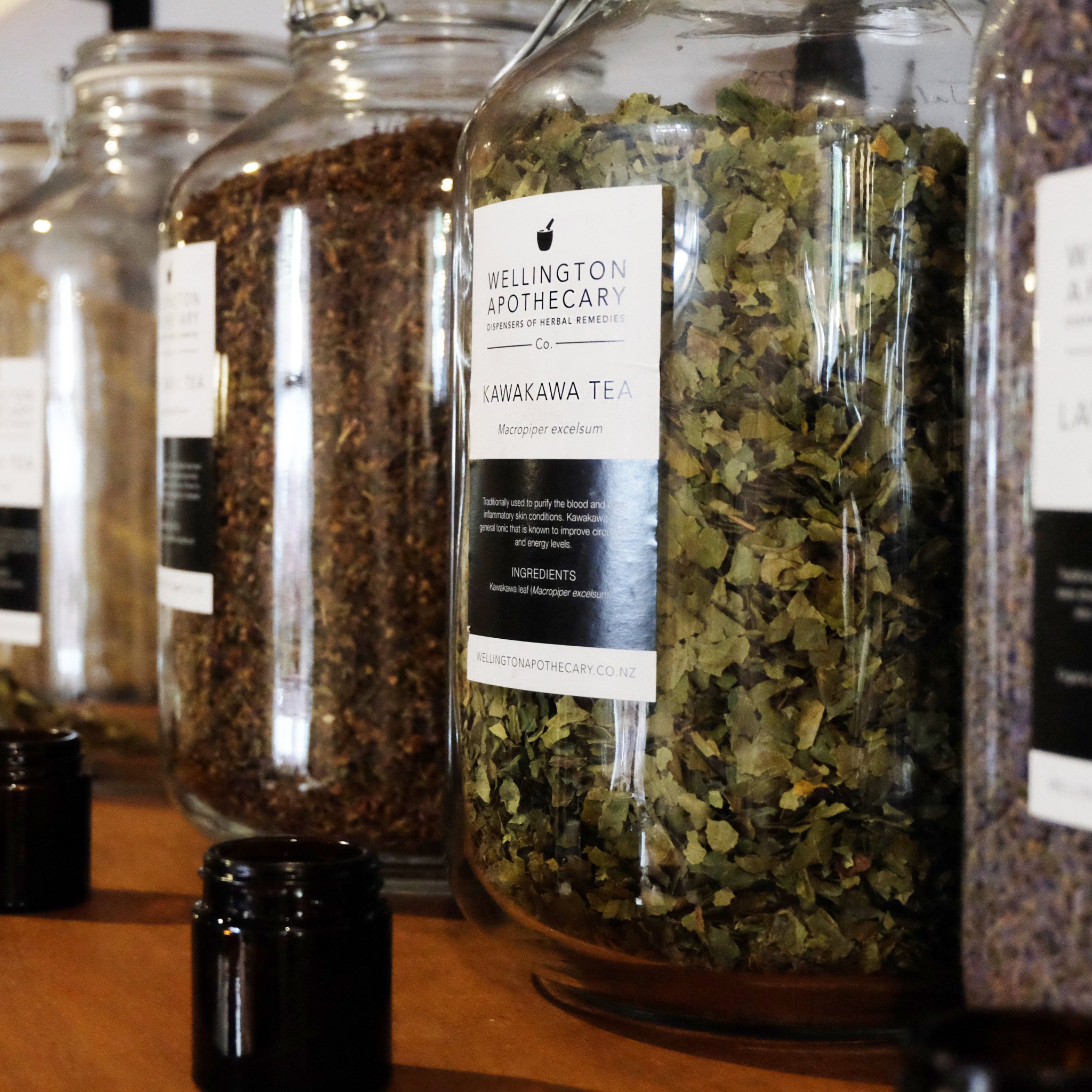 A row of large glass jars holding dried herbs.