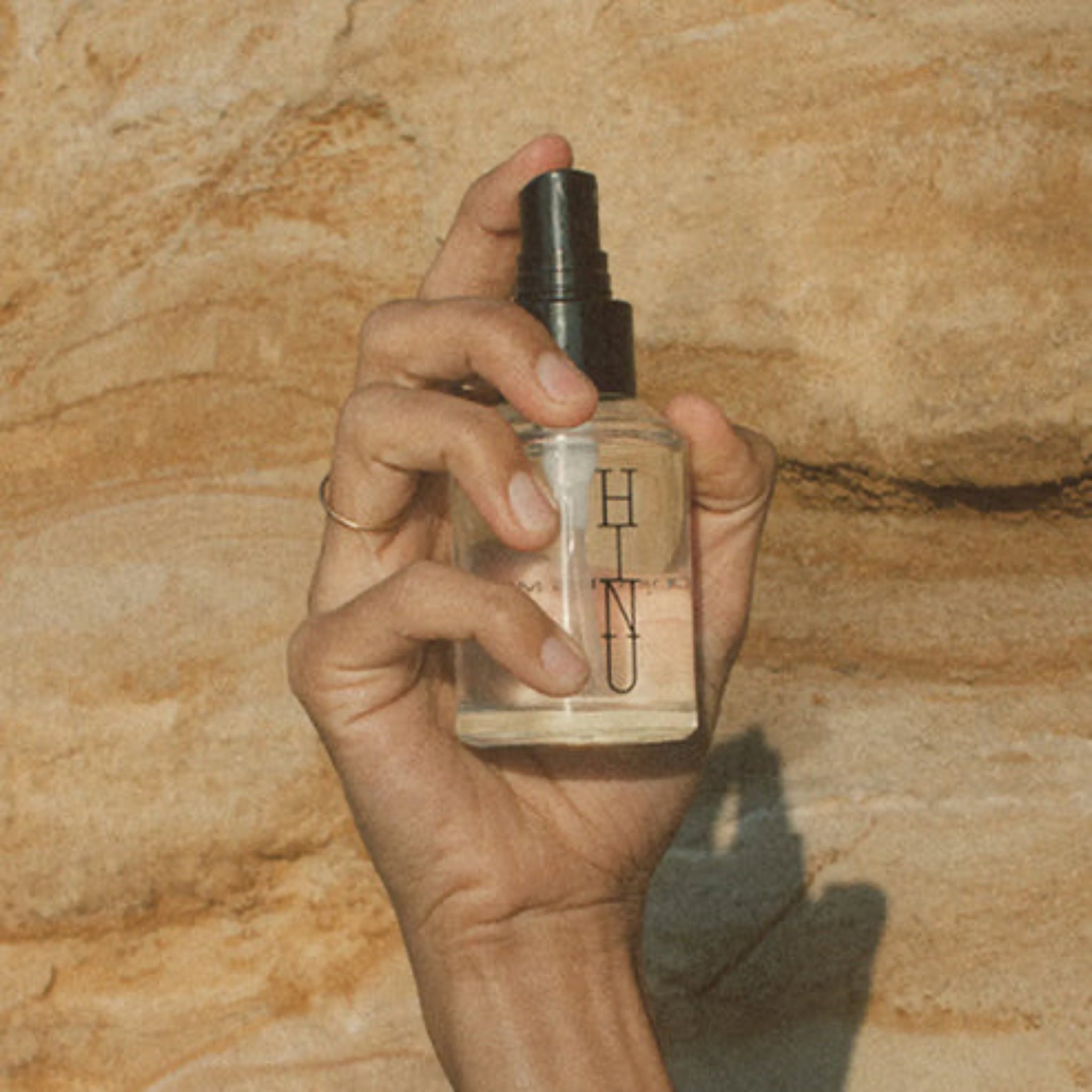Hand holding a perfume bottle labeled &