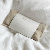 Herbal eye pillow with oat coloured linen on a white background