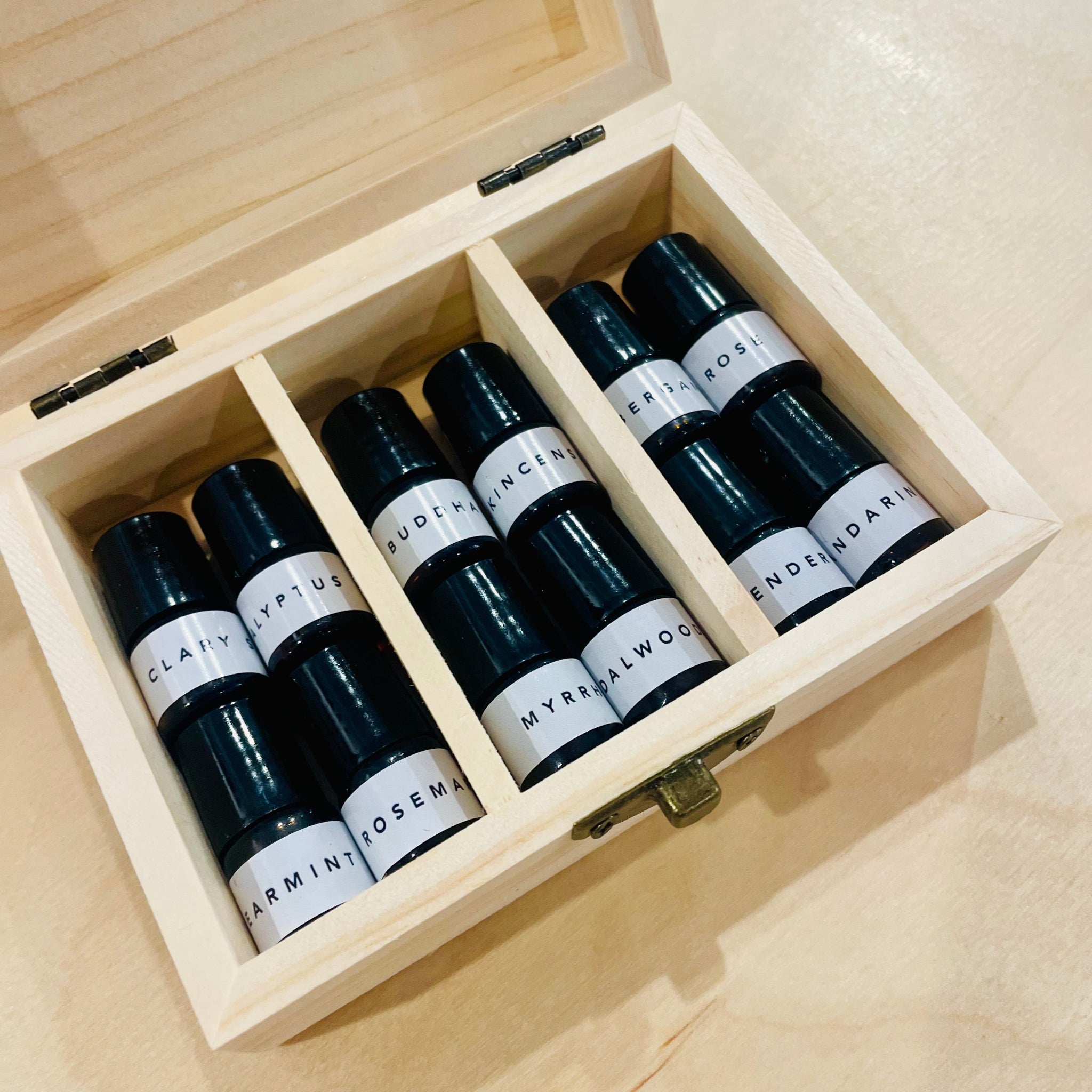 Set of essential oil bottles with white labels in a wooden box.