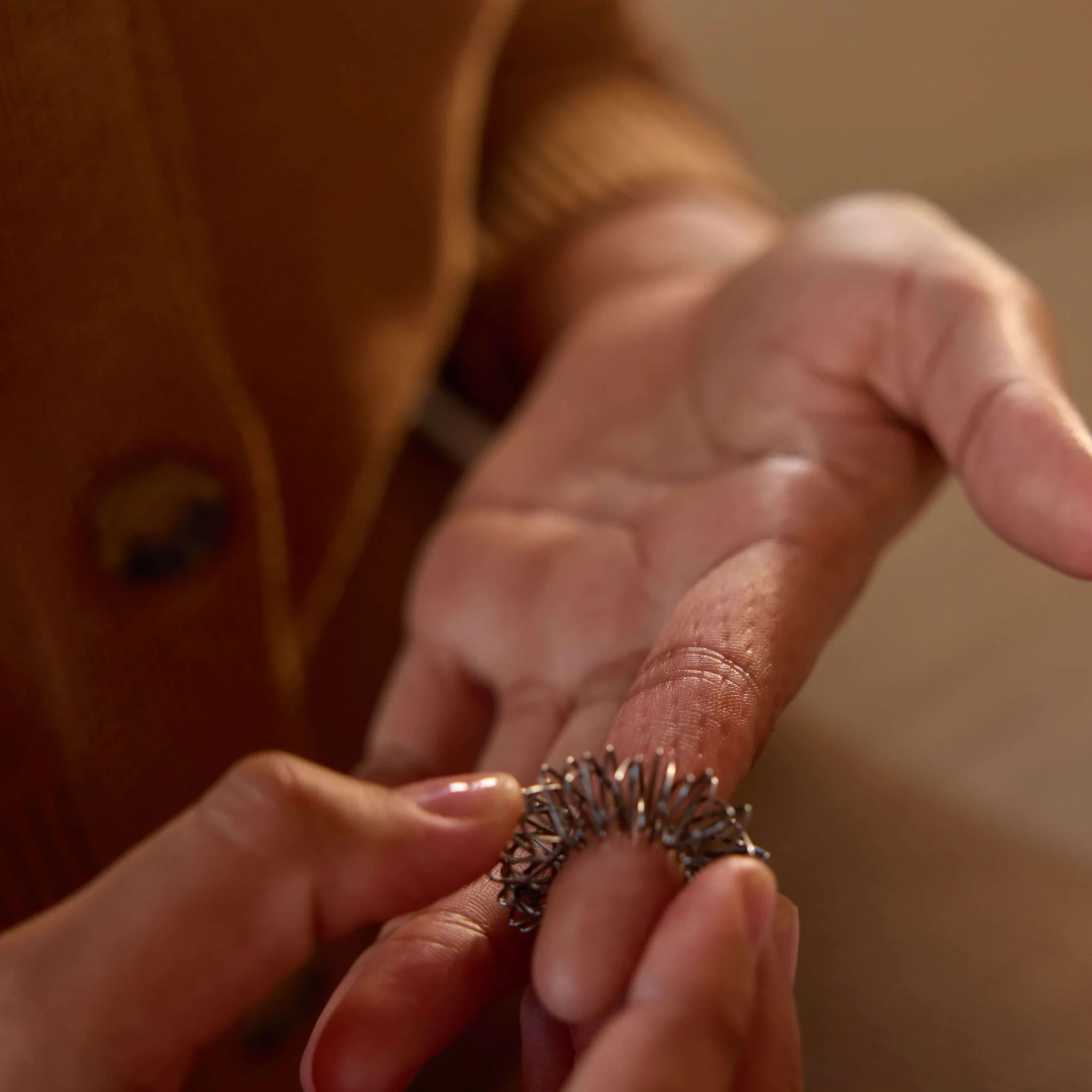 Close-up of hands holding a textured ring with a blurred background