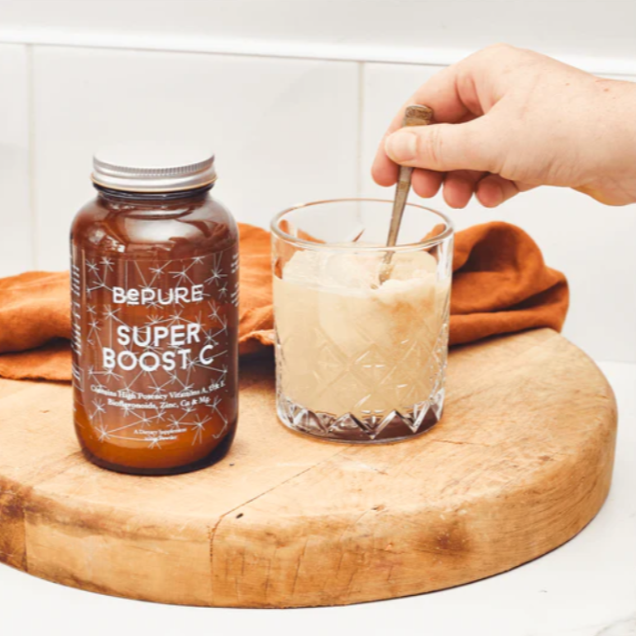 Person stirring a glass of a beverage next to a jar labeled &