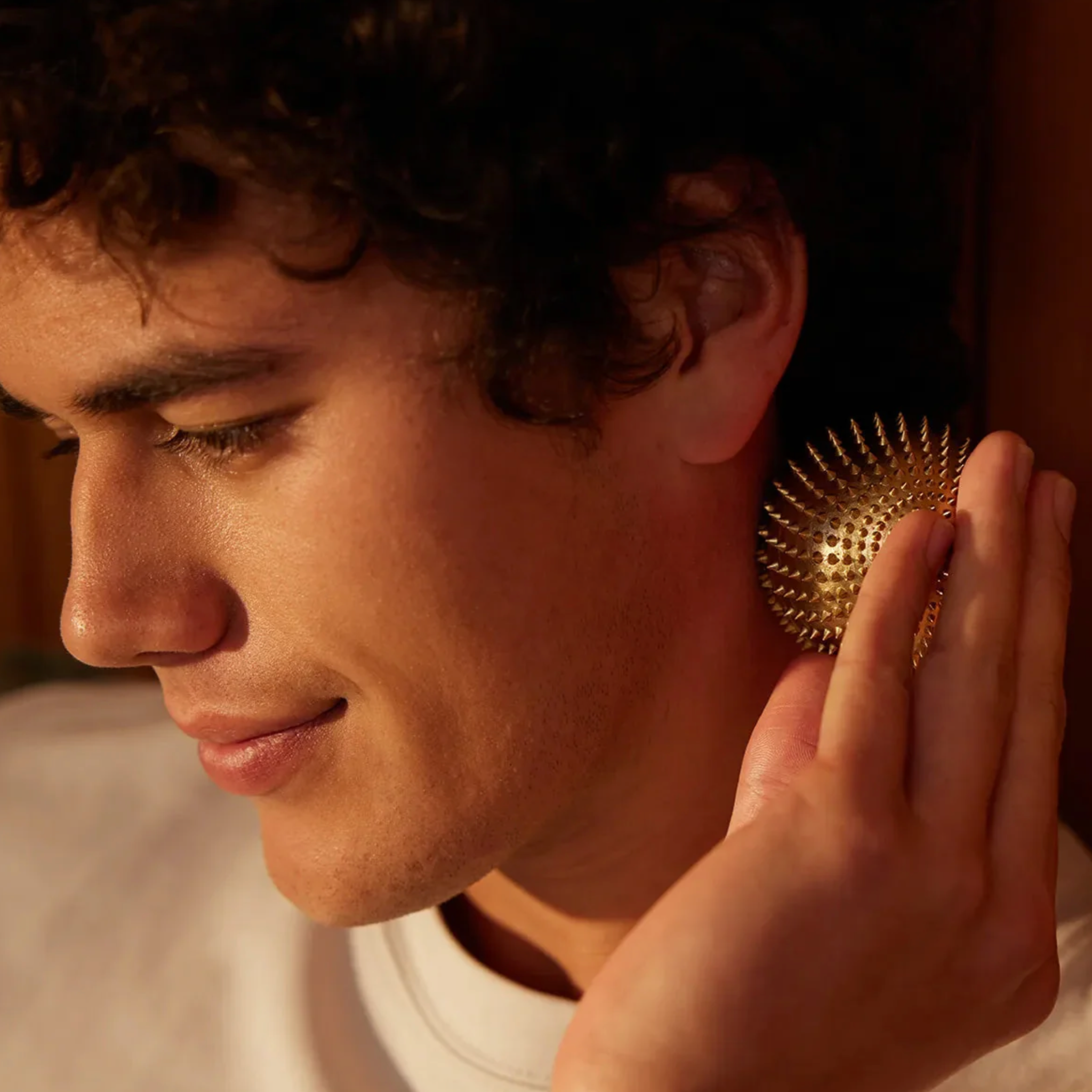 Close-up of a person using gold acupressure ball.
