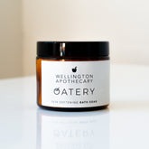 Amber glass jar on white bench with white label and black lid.