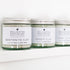 A row of glass jars containing clay powders, the first one that is in focus is bentonite clay.