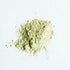 A small pile of green clay powder on white surface.