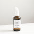 Amber glass bottle of jojoba oil on white bench.