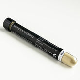 Glass test tube with black label filled with green match masque powder.