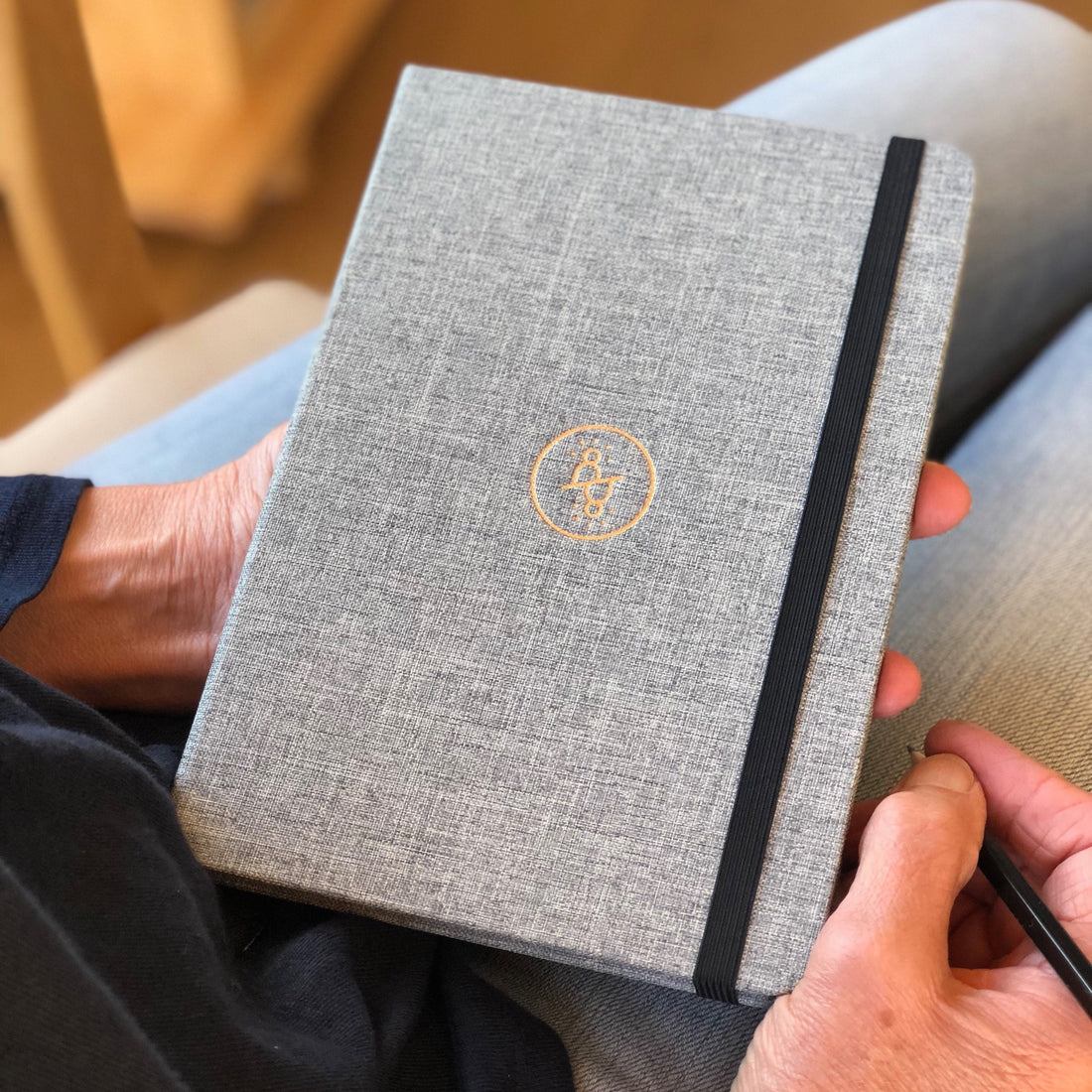 Mindfully Me journal held on lap with a pencil.