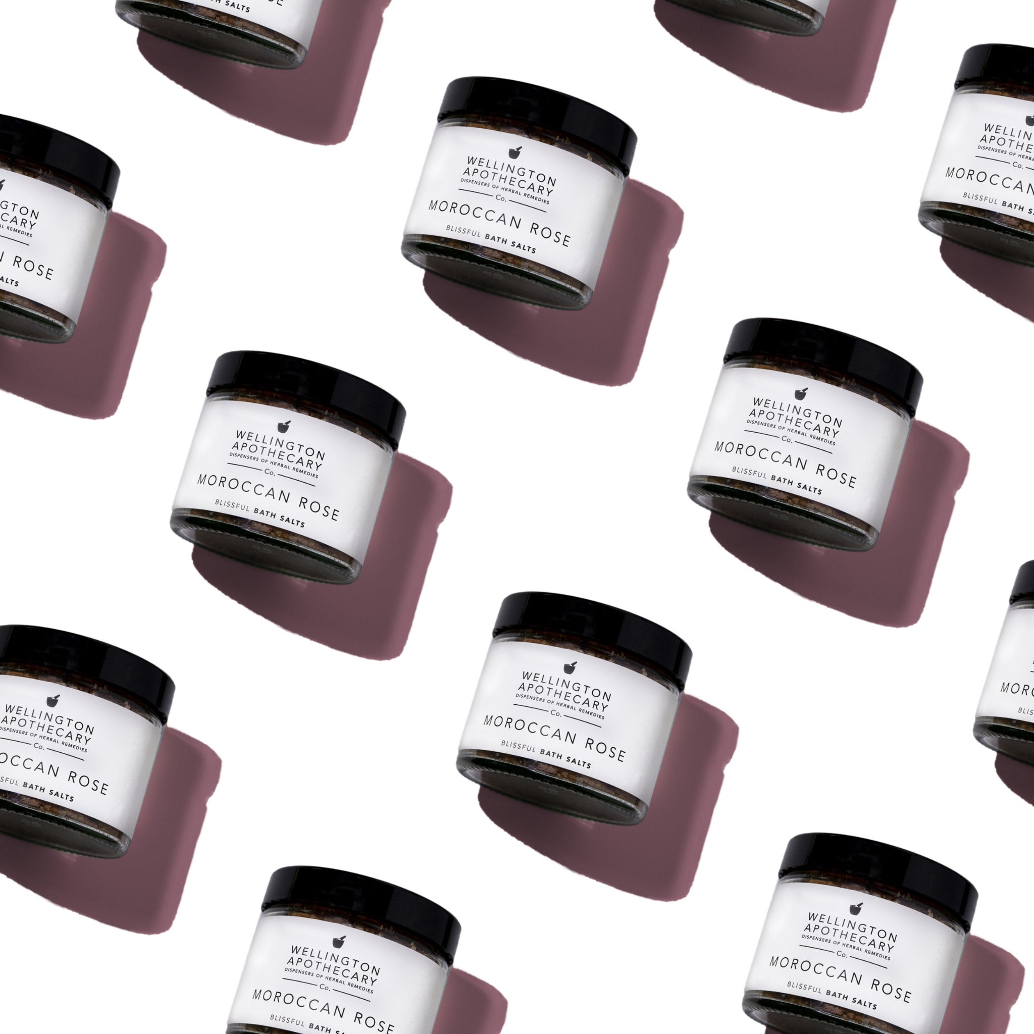 Multiple jars of Moroccan bath salts aligned geometrically on white surface.