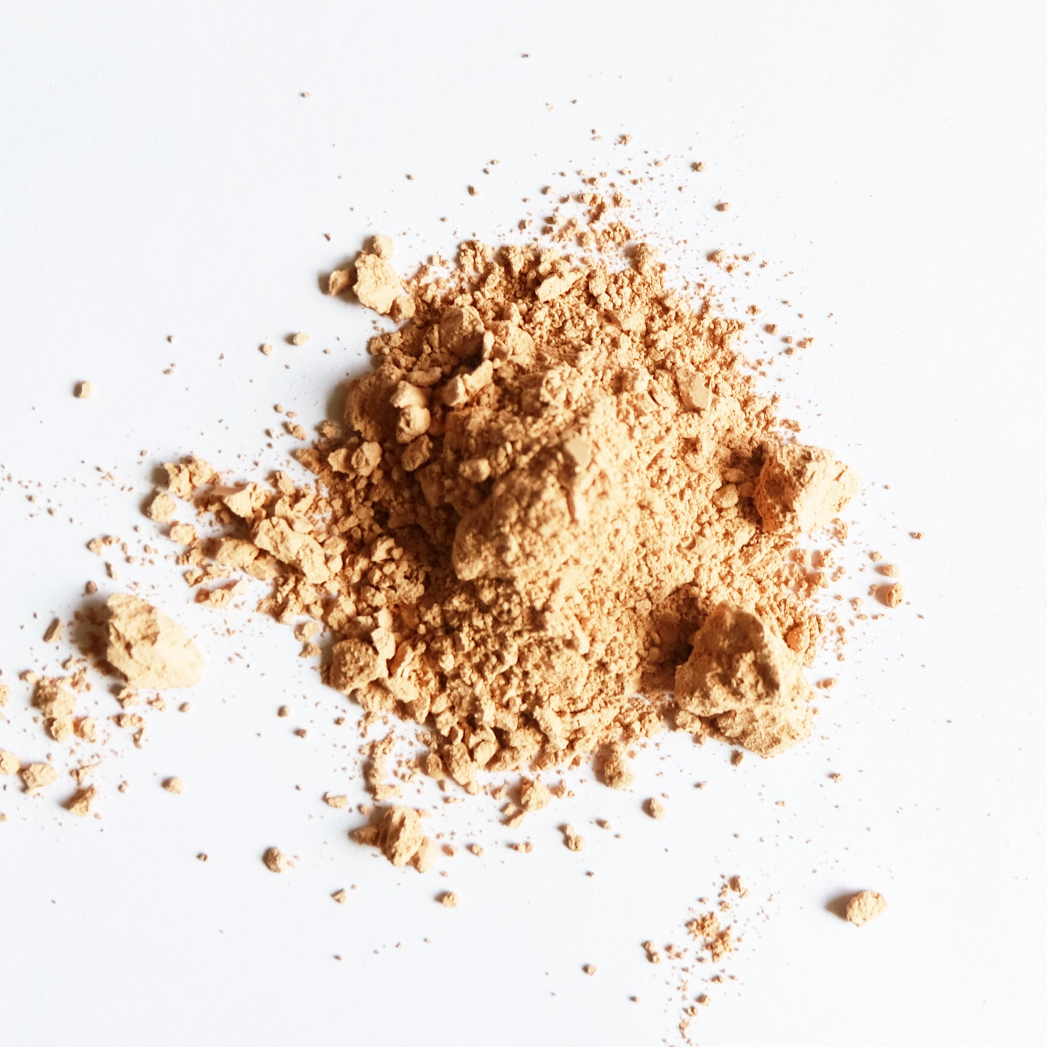 A small pile of pink clay powder on white surface.