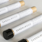 Glass test tubes lined up on white bench filled with sandalwood exfoliant powder blend.