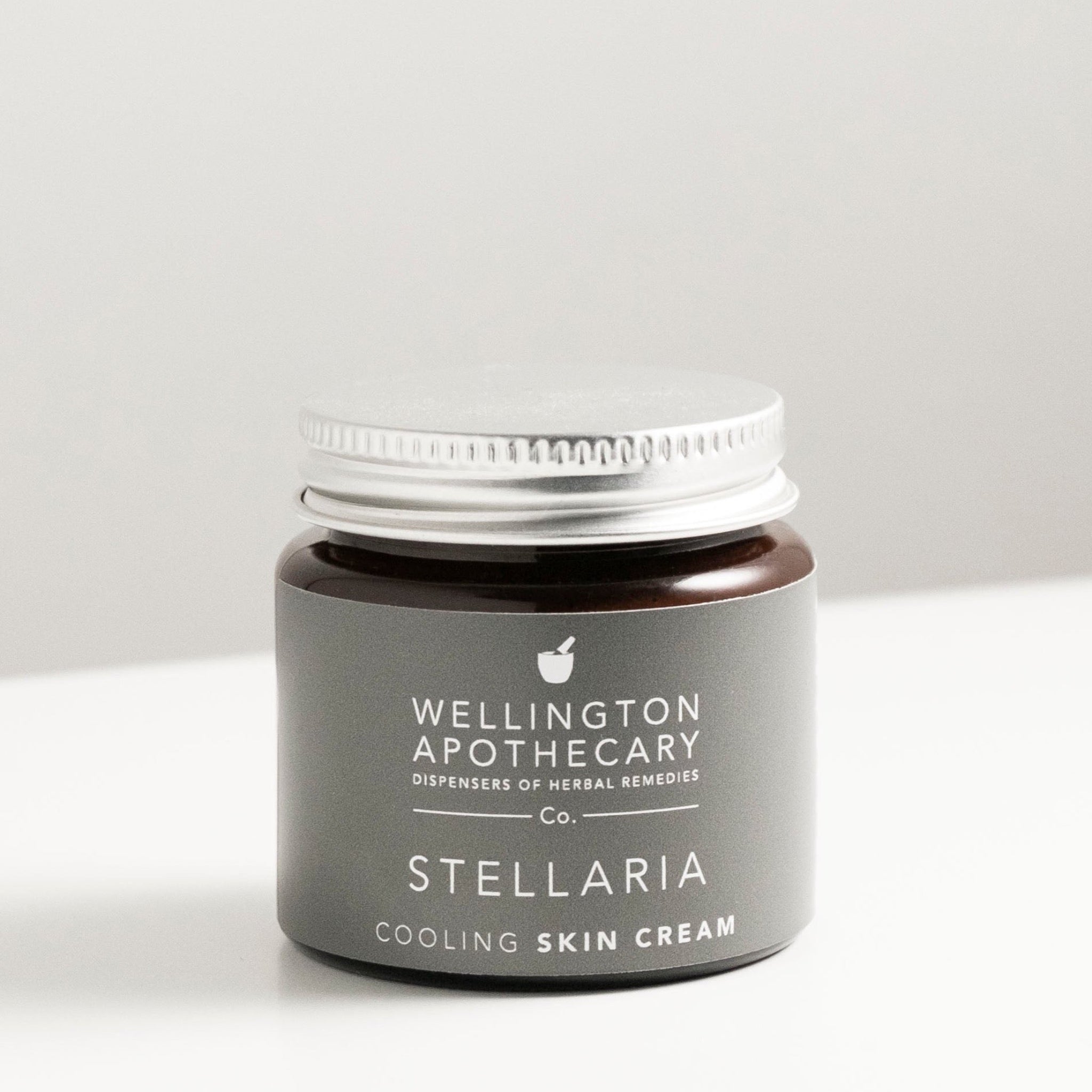 Amber glass jar of stellaria gel on white bench.