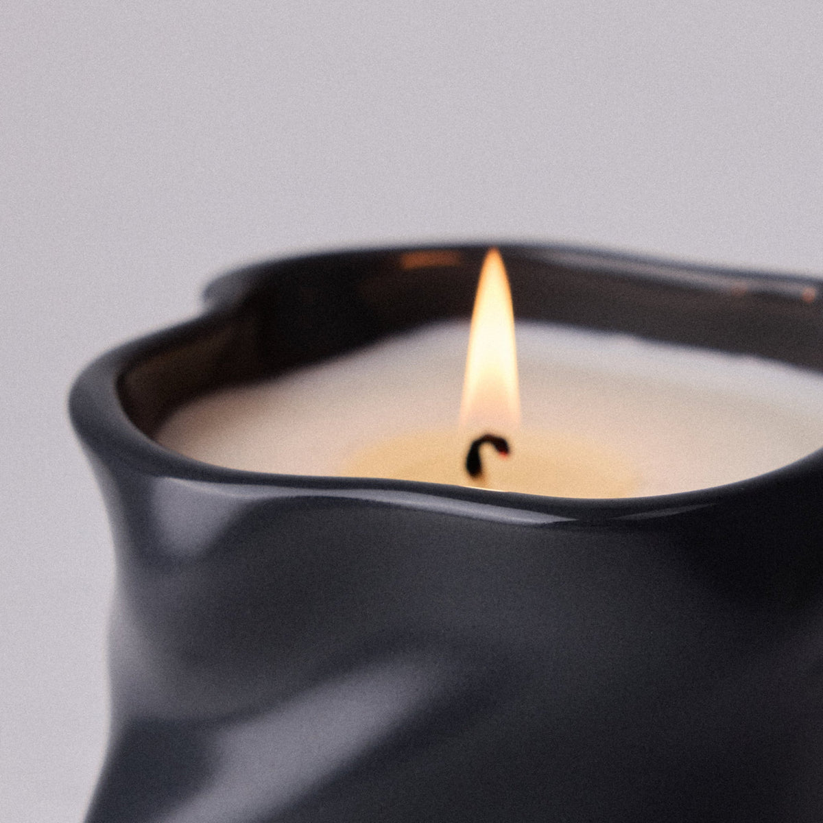 Candle in a black container with a plain background