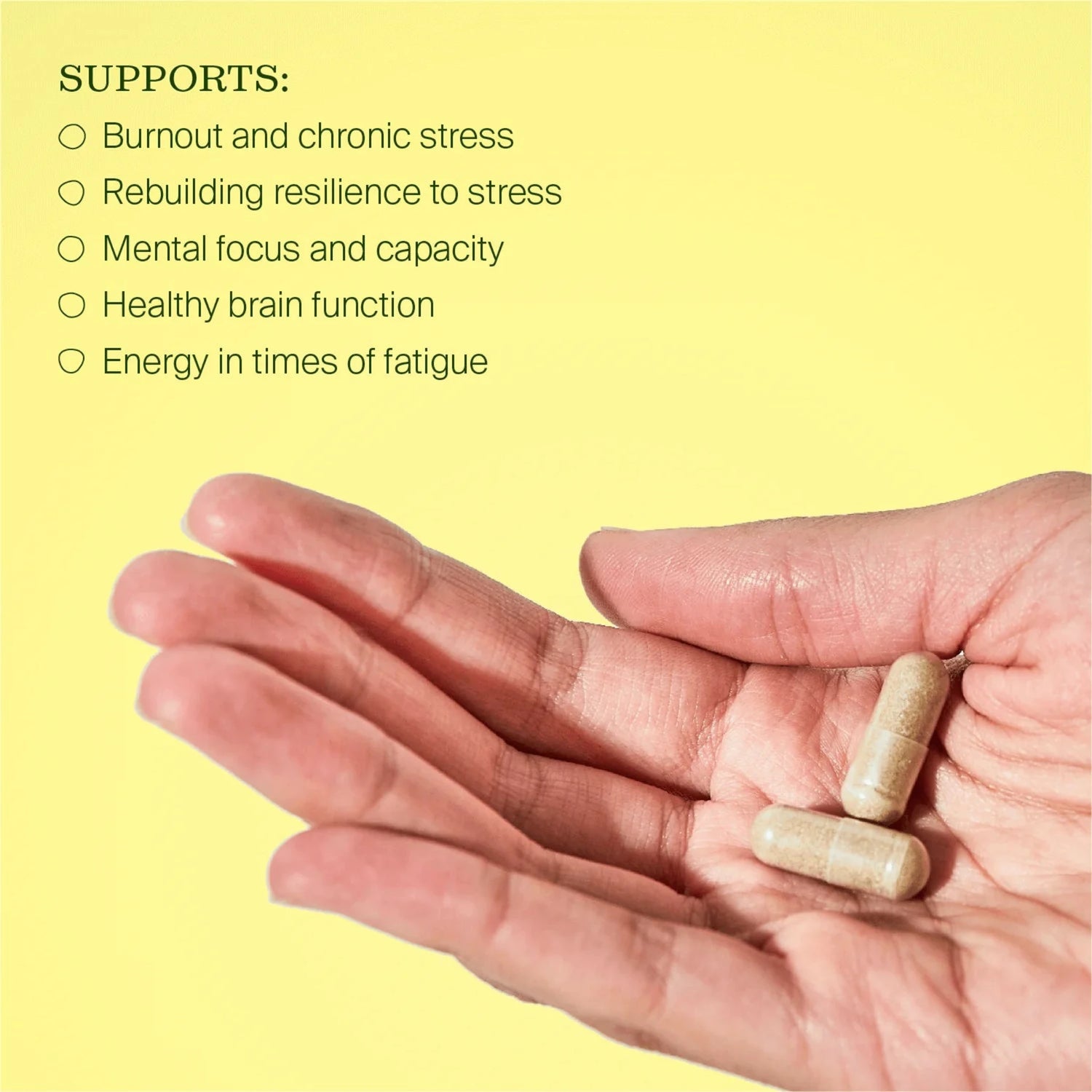 Hand holding two capsules with a list of stress support benefits on a yellow background