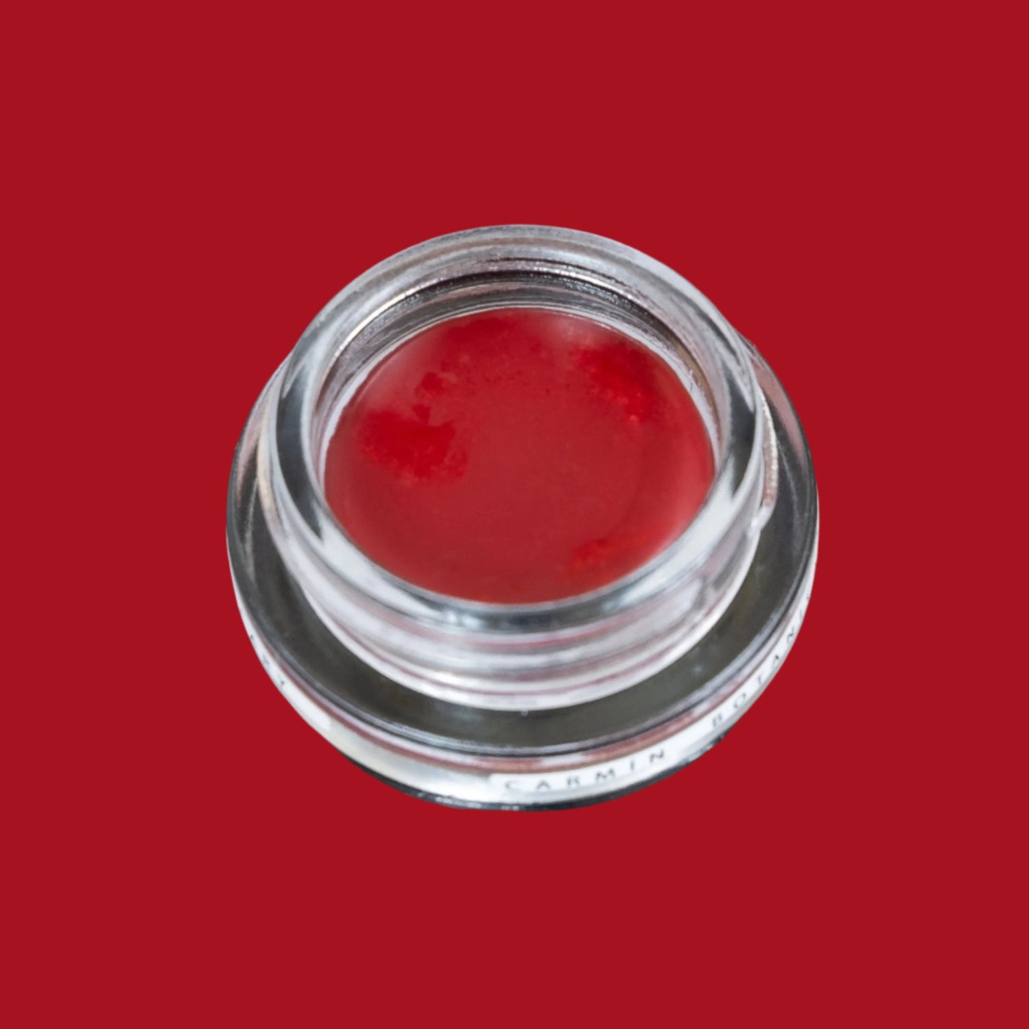 Glass pottle of Carmín lip tint, a rich, ruby red colour. 
