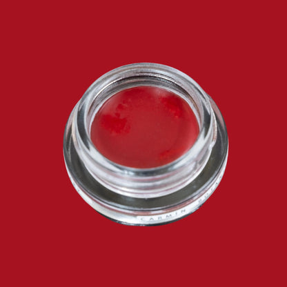 Glass pottle of Carmín lip tint, a rich, ruby red colour. 