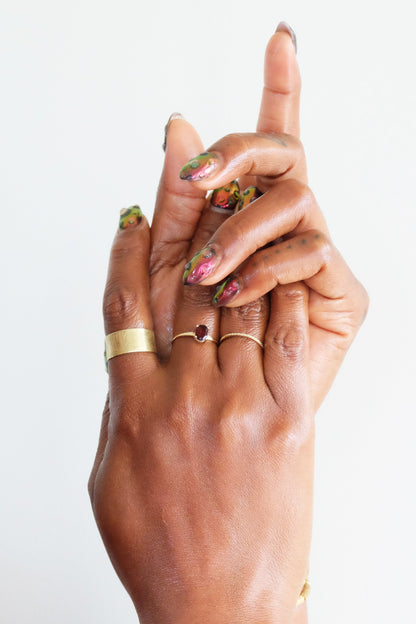 Hand with gold rings and colourful nail polish on a white background
