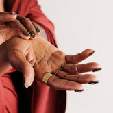 Close-up of two hands with gold rings on a plain background