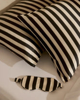 Black and white striped eye mask and pillow on a light background