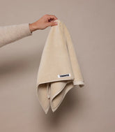 Beige towel held by a hand against a beige background