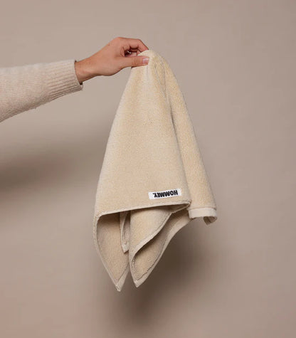 Beige towel held by a hand against a beige background