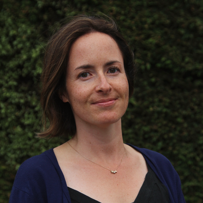 Woman standing against a green leafy background