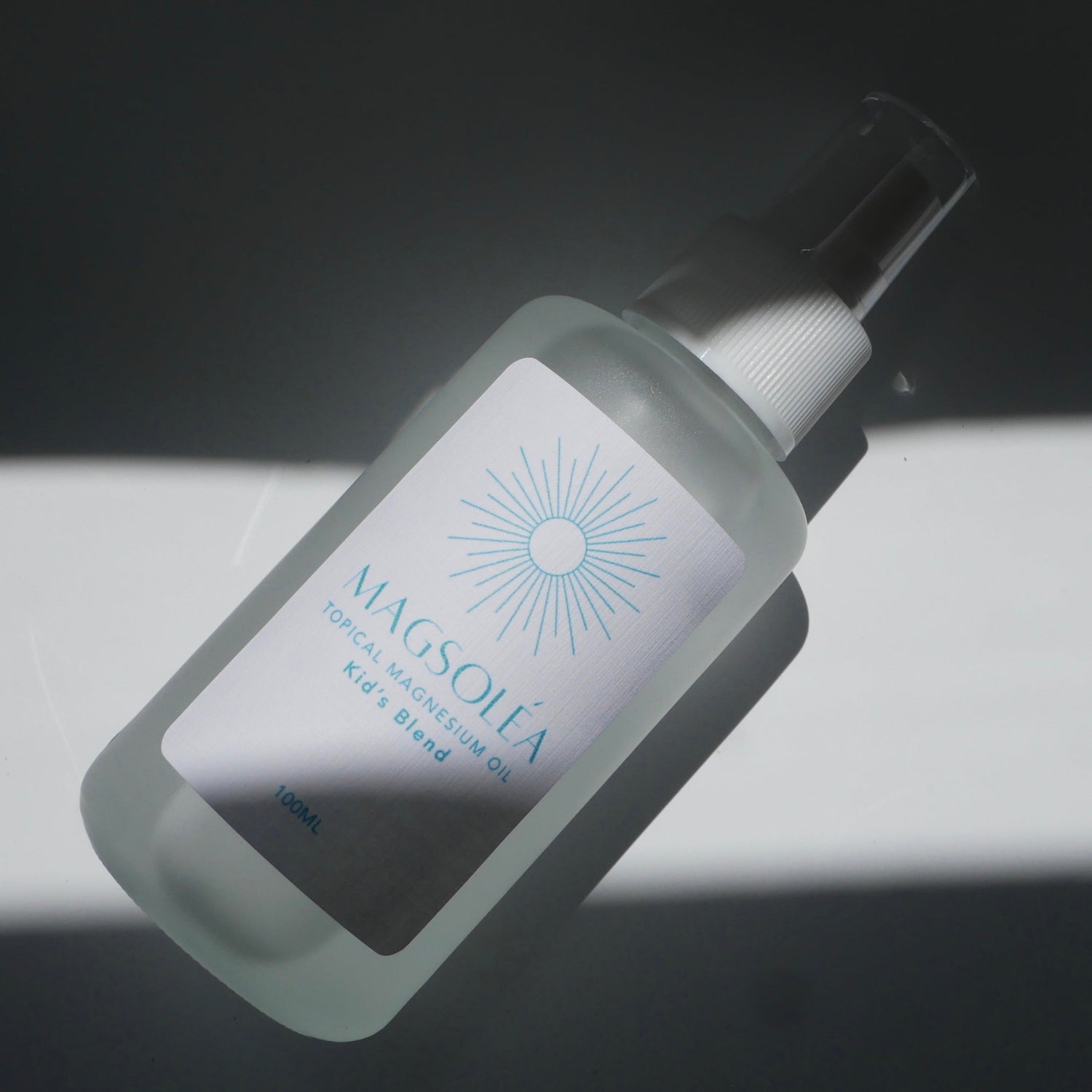 MAGSOLEA magnesium oil for kids bottle with label on a dark background