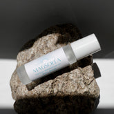 Roll-on bottle of Magsolea magnesium oil on a rock with a dark background