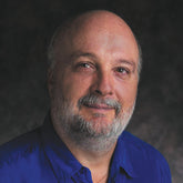 Man wearing a blue shirt against a dark background