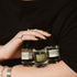 Three small bottles of perfume held by a person against a black background