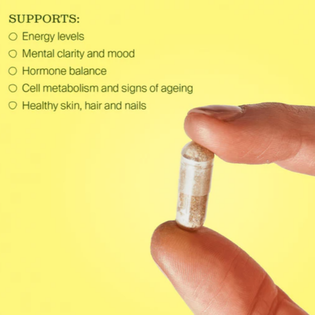 Hand holding a b-vitamin capsule with listed health benefits on a yellow background