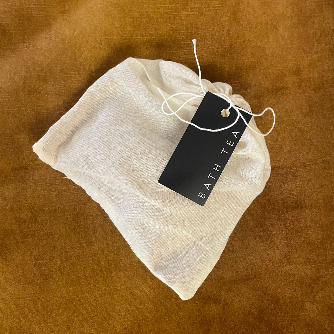 White bath tea bag with a black tag on a brown textured background
