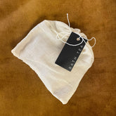 White bath tea bag with a black tag on a brown textured background