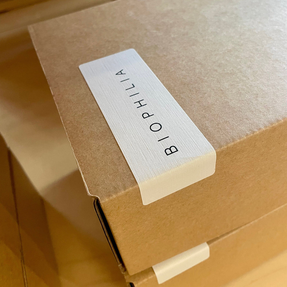 A close-up of a brown kraft paper box with a white label printed with the brand name &
