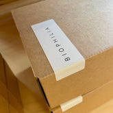 A close-up of a brown kraft paper box with a white label printed with the brand name &