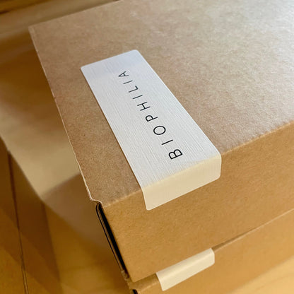 A close-up of a brown kraft paper box with a white label printed with the brand name &