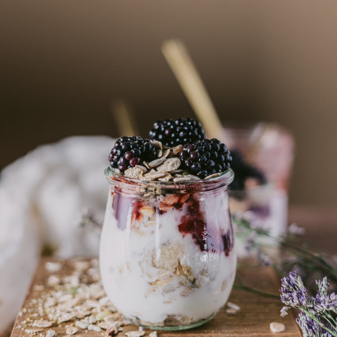Glass jar with yogurt and granola on a wooden board with blurred background