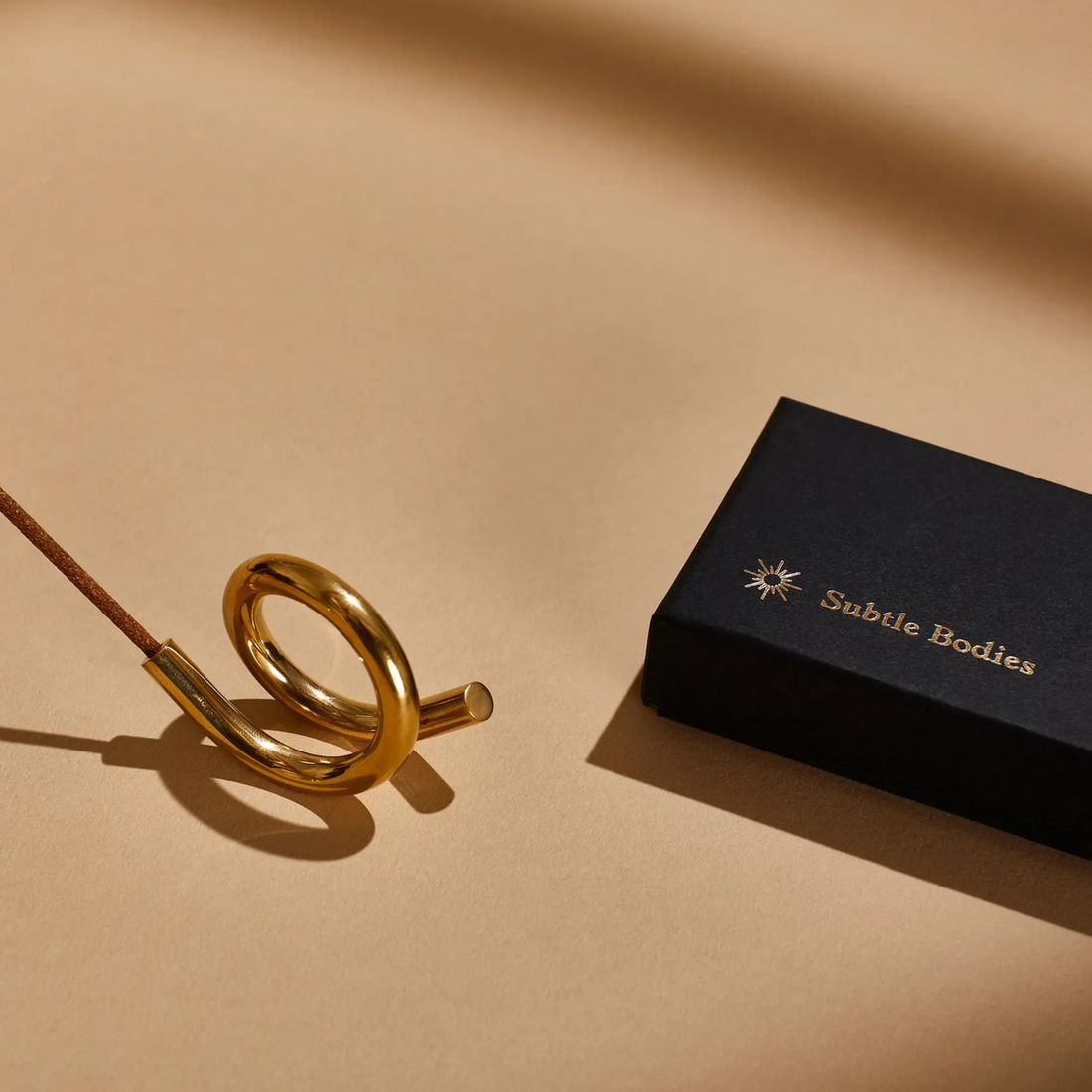 A coil shaped brass incense holder by Subtle Bodies. 