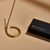 A circle shaped brass incense holder by Subtle Bodies. 