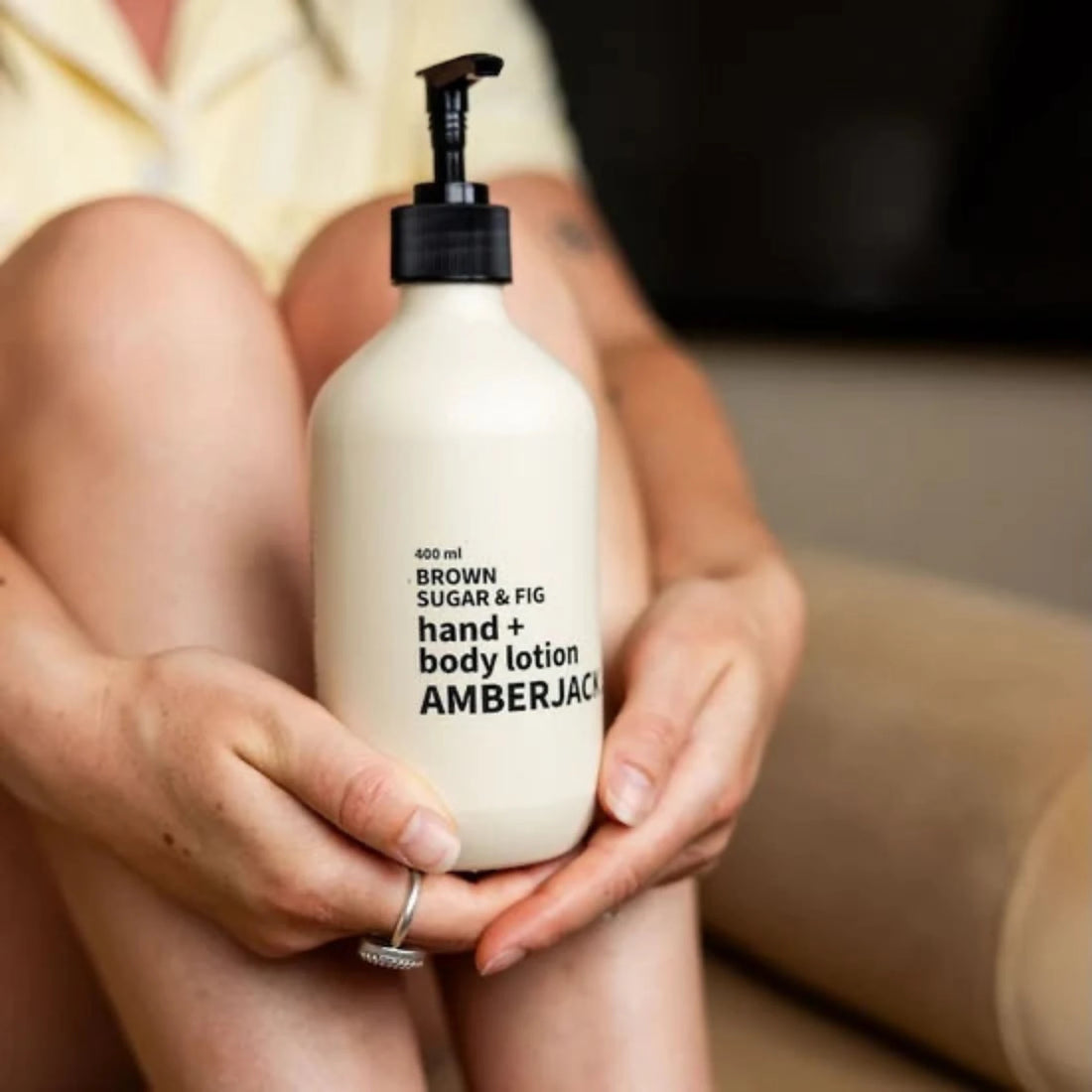 Person holding a bottle of Amberjack Brown Sugar &amp; Fig hand and body lotion.