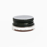 A small glass pottle of Carmín lip tint on white background. 