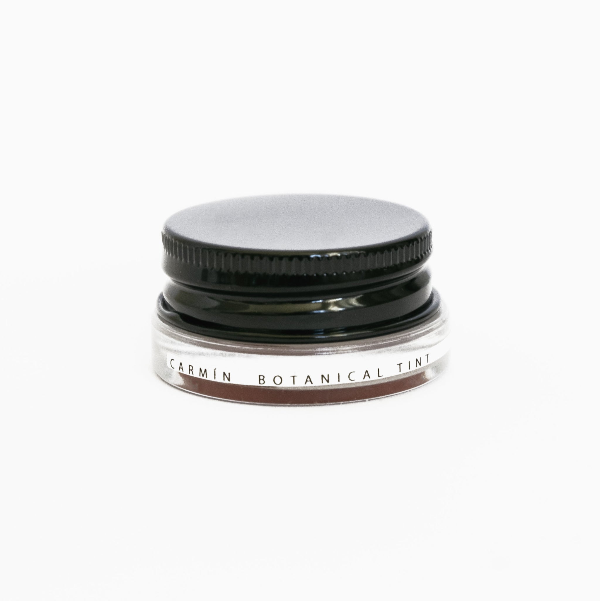 A small glass pottle of Carmín lip tint on white background. 